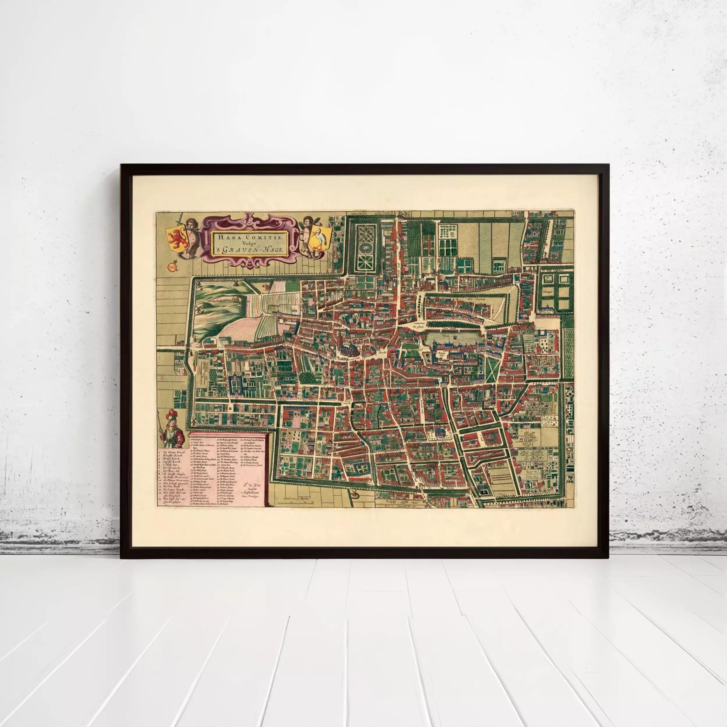 The image is a framed vintage map of a city, likely from the 16th century, displayed on a white wall.