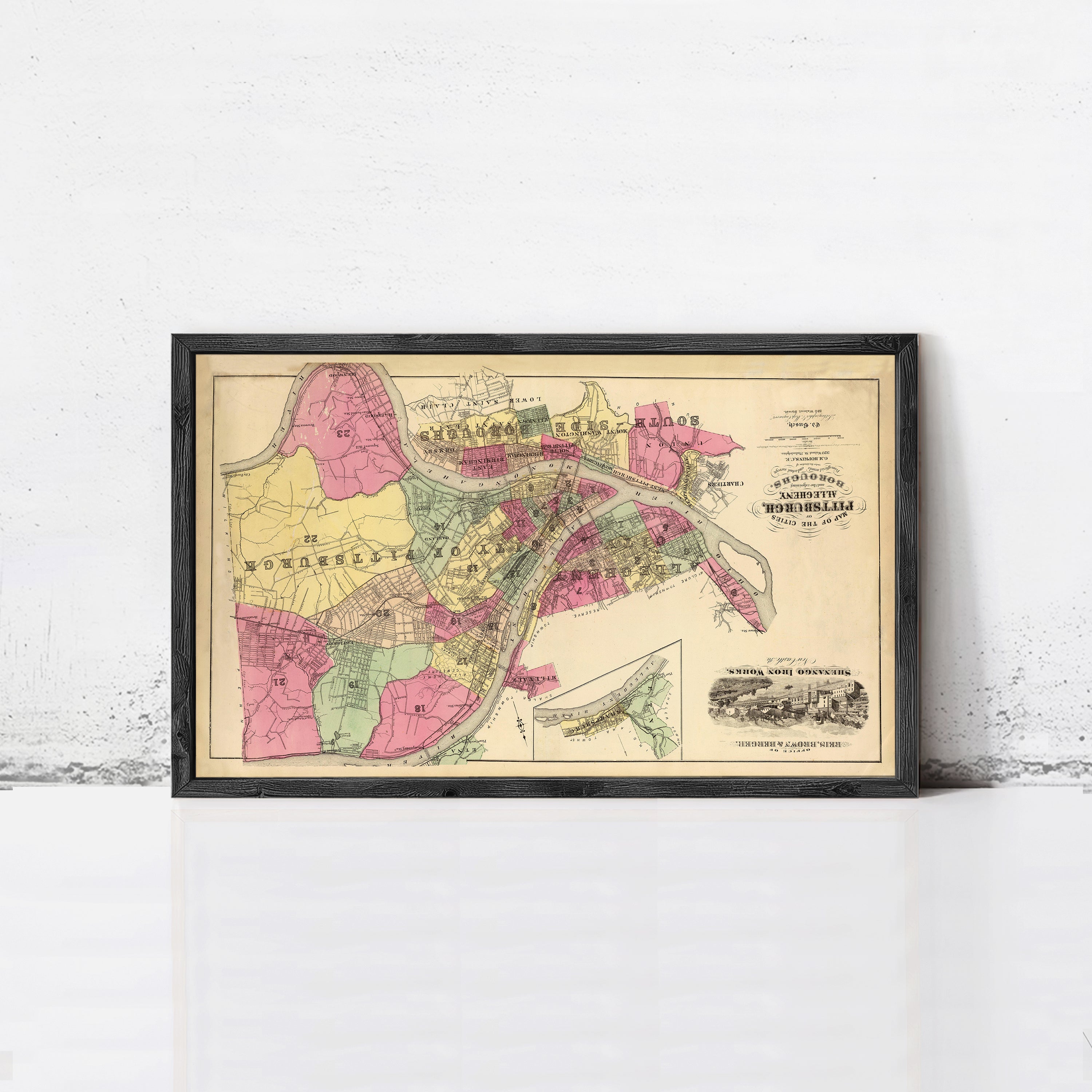 The image is a framed vintage map of a city, likely from the early 20th century, with various colored sections representing different neighborhoods or districts.