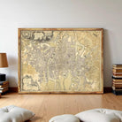 a large, framed map of a city or town, displayed on a wall in a room with a wooden floor.