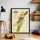 a framed map of Guatemala, with a wooden floor and a stack of books in the background.