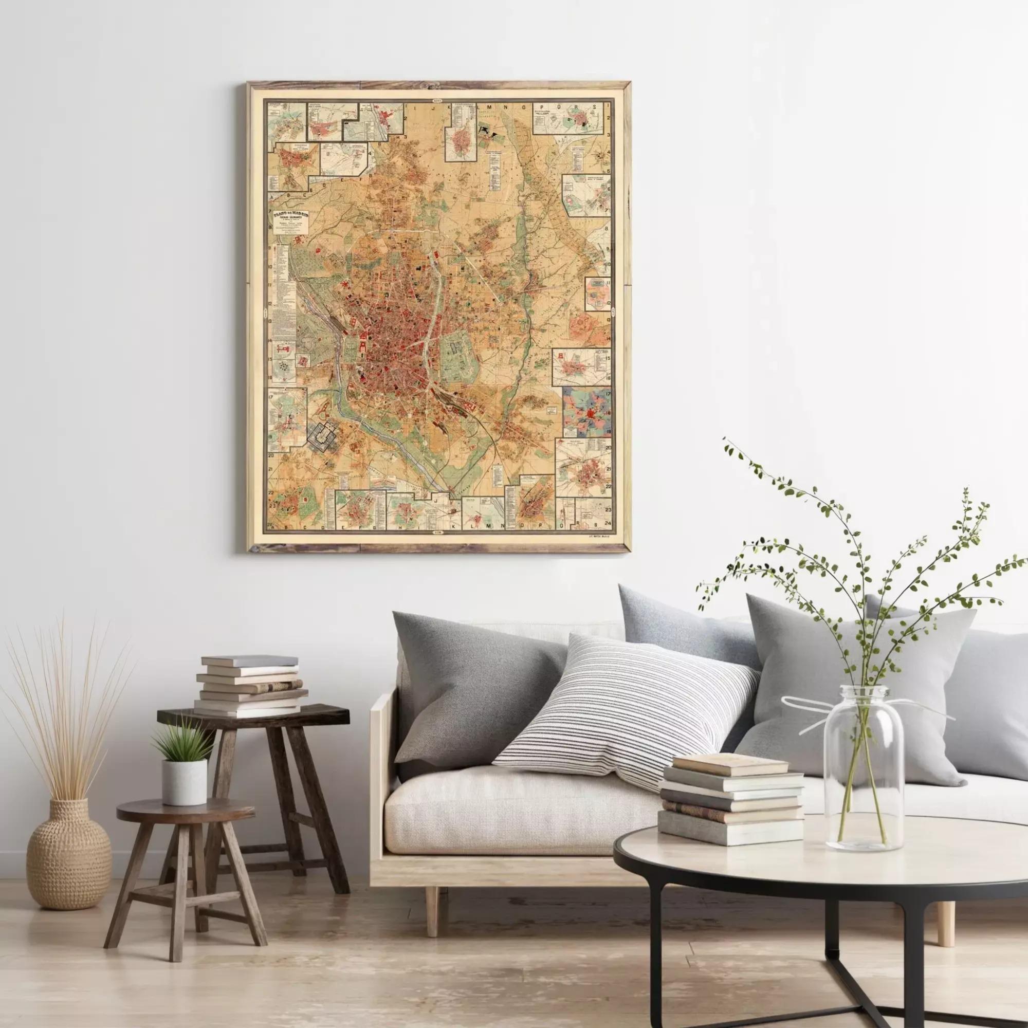 a living room with a large framed map hanging on the wall above a couch with pillows. There are also some books and a vase with flowers on the couch, creating a cozy and inviting atmosphere.