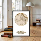 A framed map of Lowell, Massachusetts, with a wooden floor and a stack of books in the background.