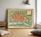 The image is a framed vintage map of a city, depicting a detailed layout of the streets, buildings, and surrounding landscape.