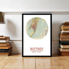 A framed map of India with the city of Mumbai highlighted, placed on a wooden floor next to a stack of books.