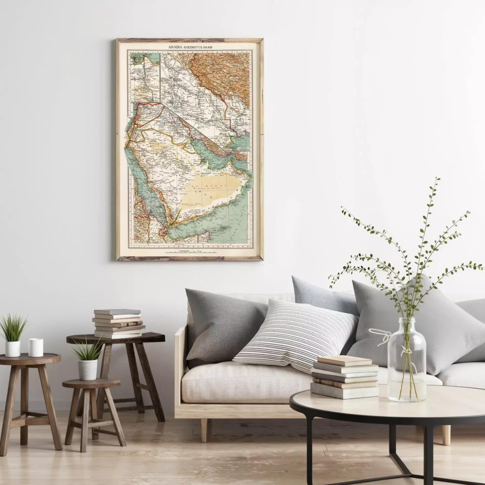 a living room with a large framed map of the Middle East hanging on the wall above a gray sofa with striped pillows. The room also includes a coffee table with a vase of greenery, a stack of books, and a small side table with a plant.