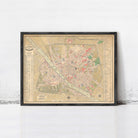 The image is a framed vintage map of a city, likely from the 19th century, displayed on a white wall.