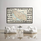 a large framed map of a region hanging on a wall, with a small table and two white bean bag chairs positioned in front of it.