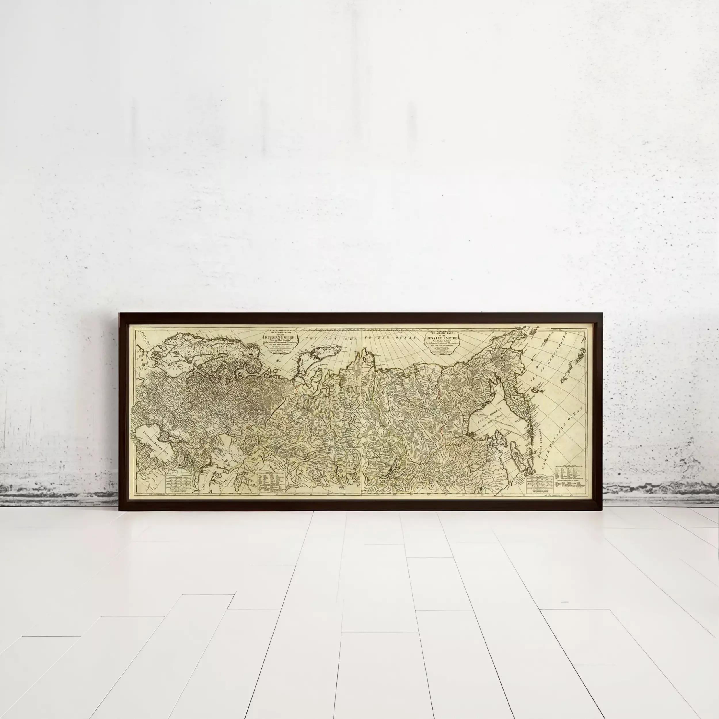 A framed antique map of the world is displayed against a white wall.