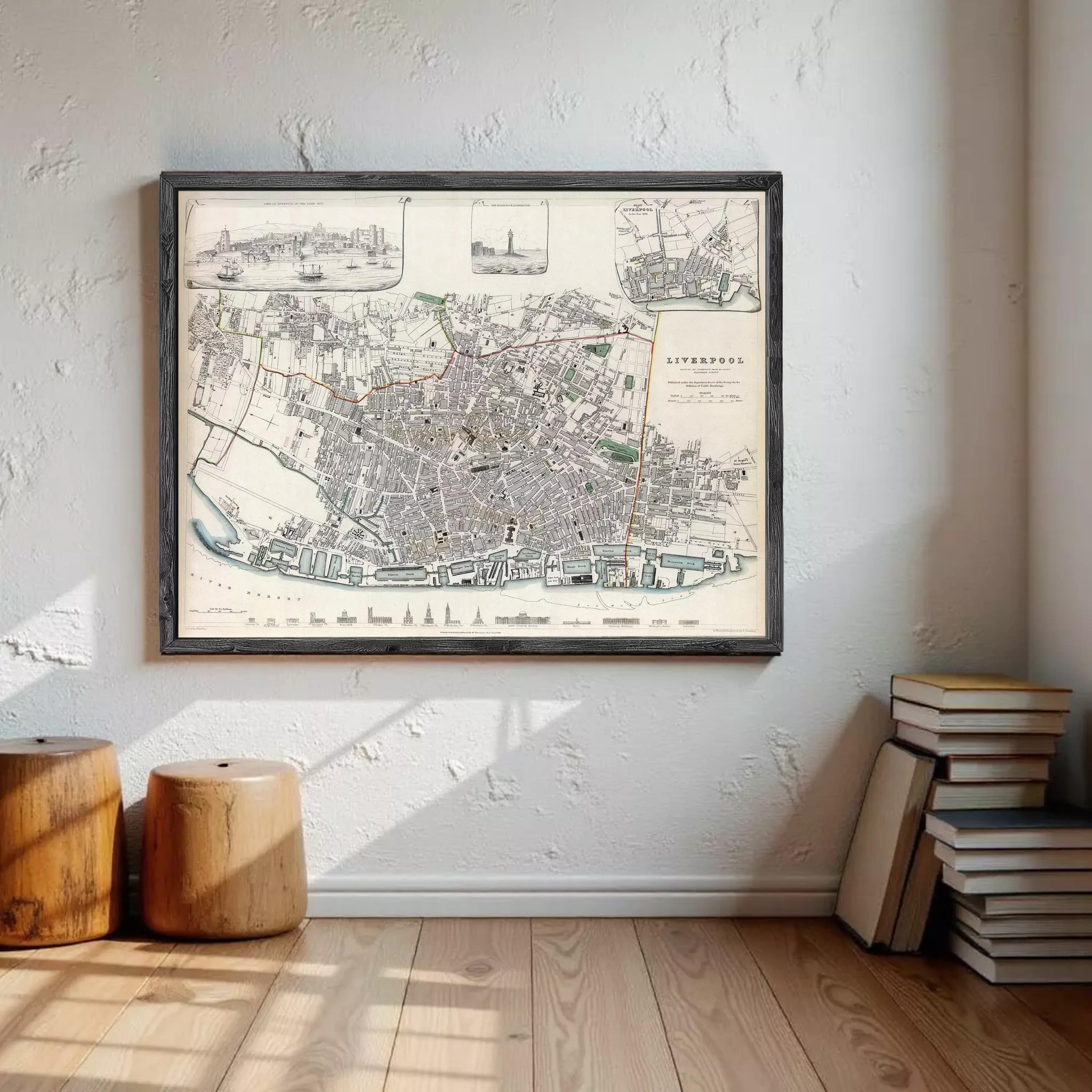 a large framed map of London hanging on a wall, with a stack of books and a wooden stool in the foreground.