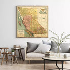 a large framed map of British Columbia, Canada, hanging on a wall above a couch and a coffee table in a living room setting.