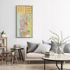 a living room with a large wall-mounted map of Tel Aviv, Israel, above a gray sofa with striped pillows. The room also includes a coffee table with books and a vase of greenery.