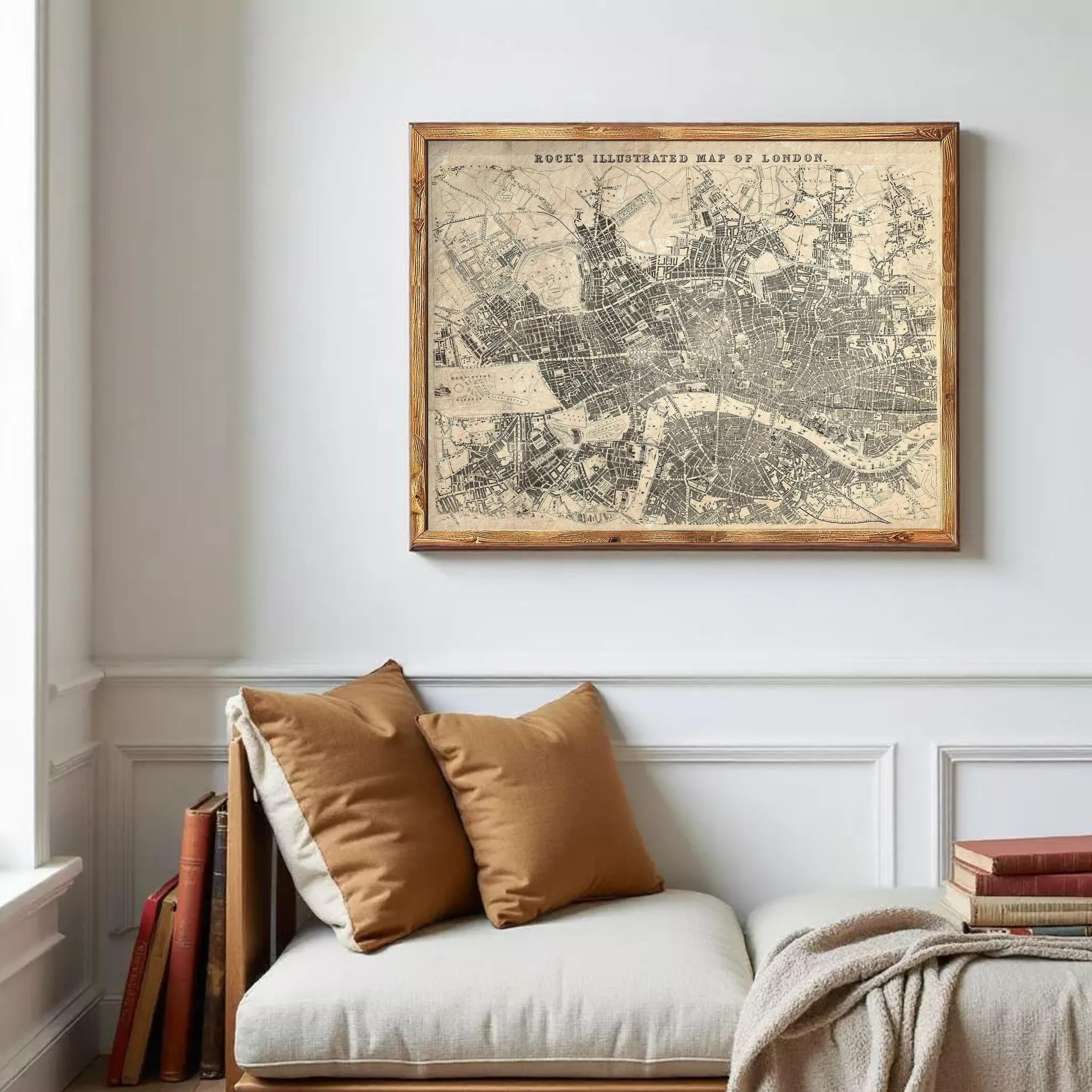 a framed vintage map of London hanging on a wall above a white couch with two brown throw pillows.