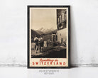 A framed vintage travel poster depicting a scenic mountain landscape in Switzerland, with two people walking along a path in the foreground.
