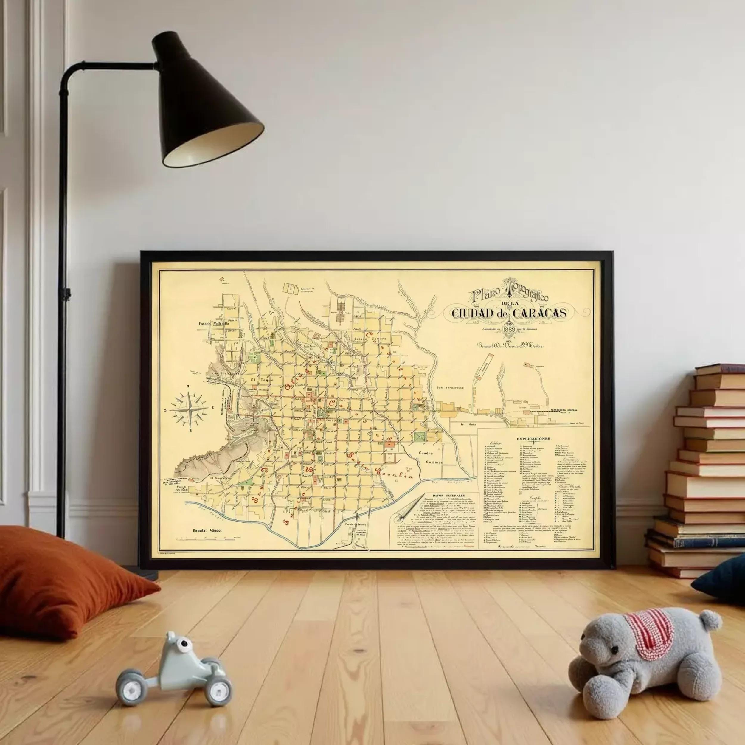 a large framed map of a city, with a lamp and a stack of books on the floor in front of it. There is also a small toy car and a stuffed animal on the floor.