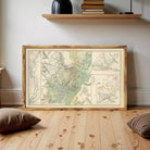 a large framed map of the United States, with a wooden shelf and a stack of books in the background.