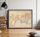 The image is a framed vintage map of a city, likely from the early 20th century, depicting the city's layout and surrounding areas.
