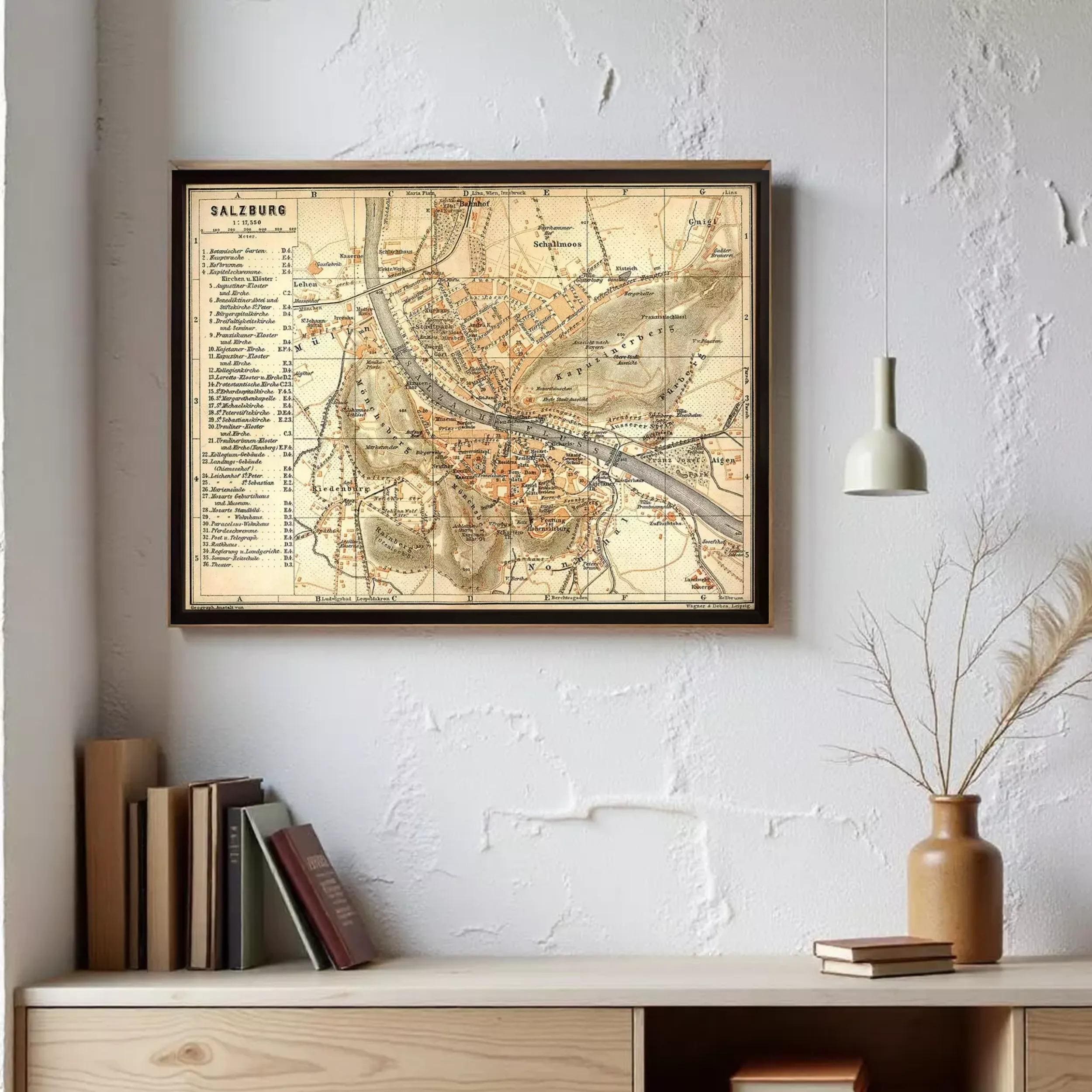 a framed map of Salzburg hanging on a wall, with a shelf below it containing books and a vase.