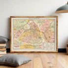 a large framed map of a city, with a wooden floor and a lamp in the background.