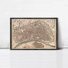 The image is a framed antique map of a city, depicting a detailed layout of the streets, buildings, and other urban features.