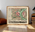 The image is a framed vintage map of a city, depicting a detailed layout of streets, buildings, and other urban features.