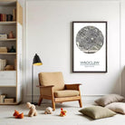 a cozy living room with a wooden chair, a lamp, and a framed map of Wrocław, Poland, which is the capital city of Poland. The room also contains a bookshelf filled with books and various knick-knacks, as well as a collection of stuffed animals.