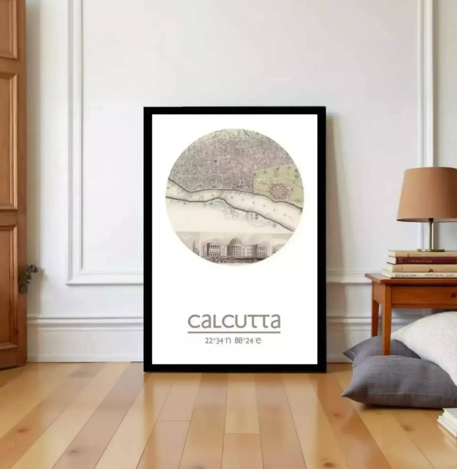 a framed poster of Calcutta, India, with a map of the city displayed on it. The poster is placed on a wooden floor in a room with a lamp and some books visible in the background.