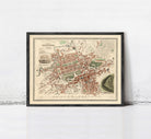 The image is a framed vintage map of a city, depicting a detailed layout of streets, buildings, and other urban features.