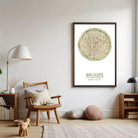 a cozy living room with a wooden chair, a lamp, and a framed map of Brussels.