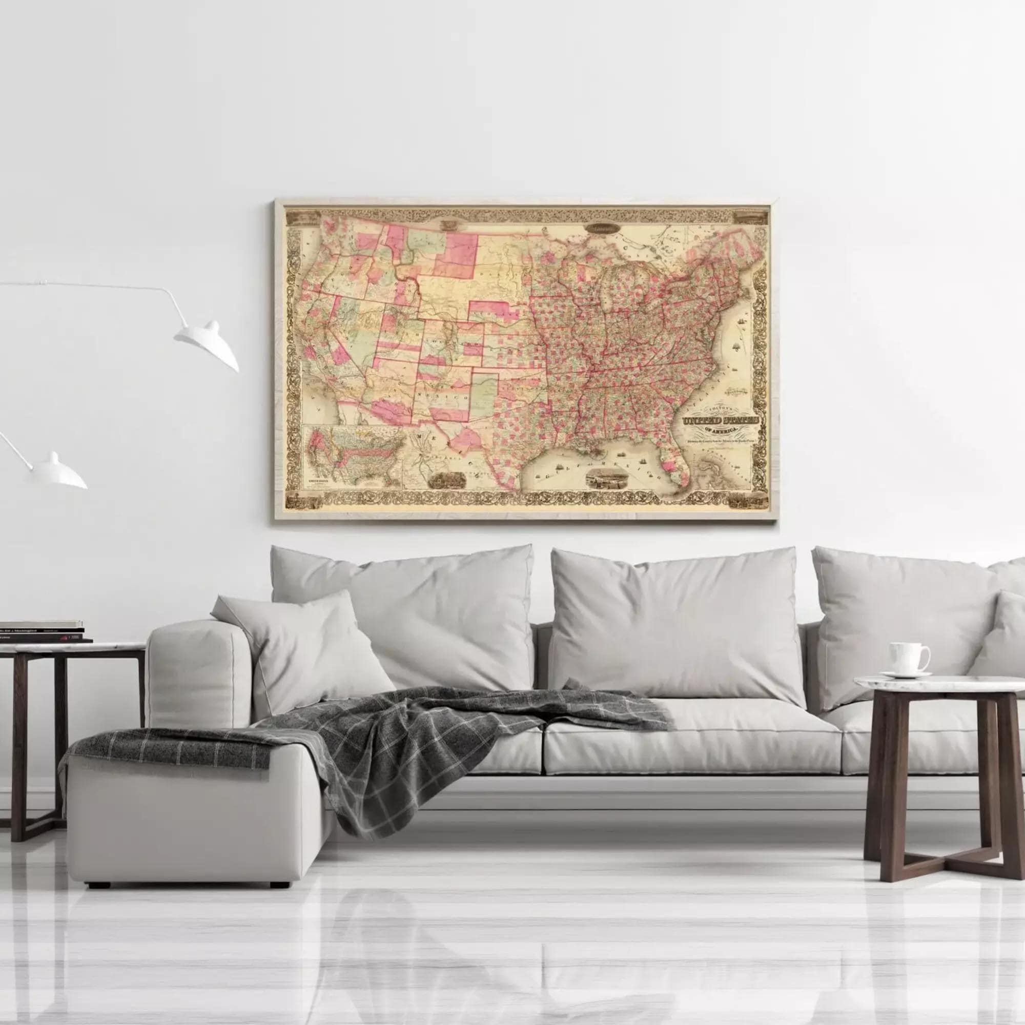 a large, colorful map of the United States hanging on a wall above a gray couch in a living room setting.