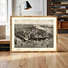 A framed black and white illustration of New York City, depicting the cityscape with boats and buildings, is displayed on a wooden surface.
