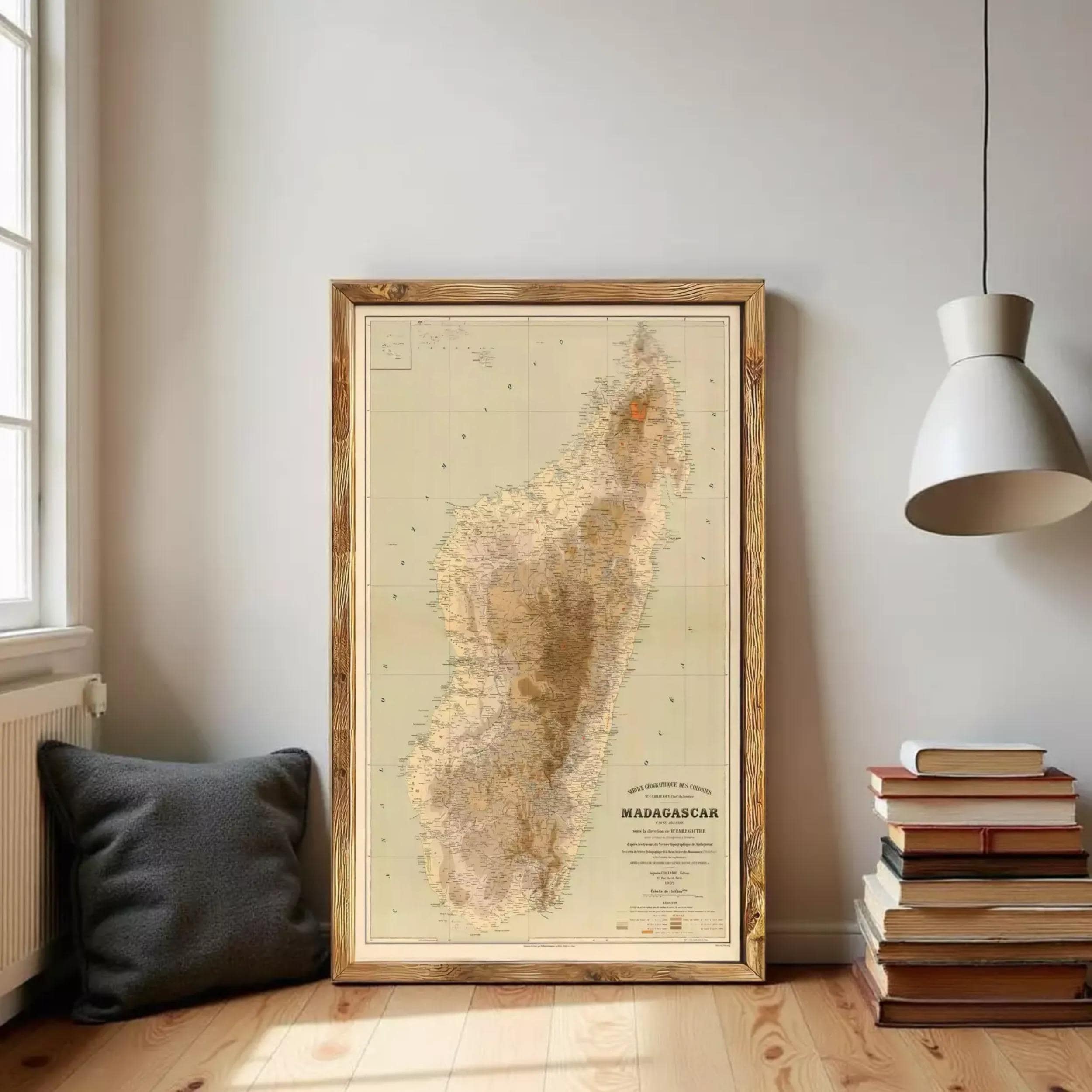 a large framed map of Madagascar, with a stack of books and a lamp in the background.