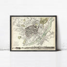 The image is a framed vintage map of a city, depicting a detailed layout of streets, buildings, and other urban features.