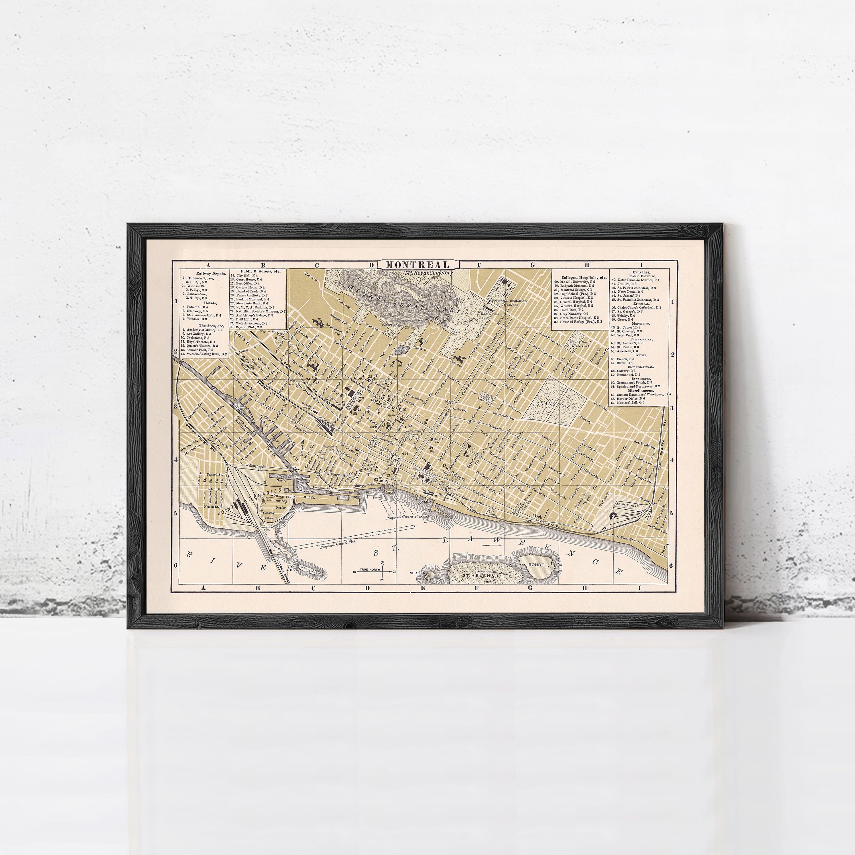 The image is a framed vintage map of a city, likely from the 19th century, displayed on a wall.