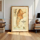 a large framed map of Argentina, with a wooden frame and a vintage style. The map is displayed on a wall, surrounded by a stack of books and a lamp.