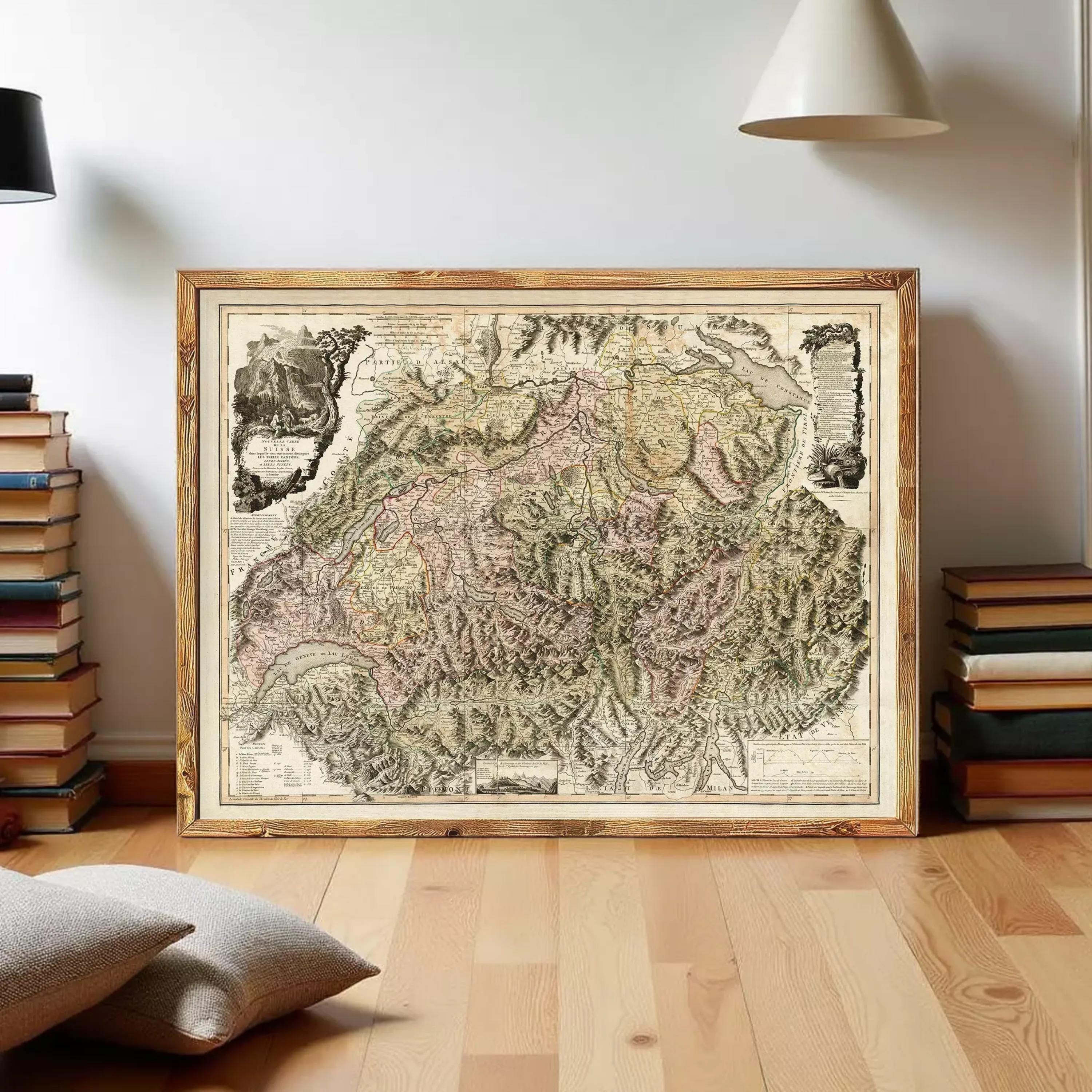 a large framed map of a mountainous region, with a wooden frame and a vintage appearance. The map is displayed on a wooden floor, surrounded by a stack of books and a lamp.