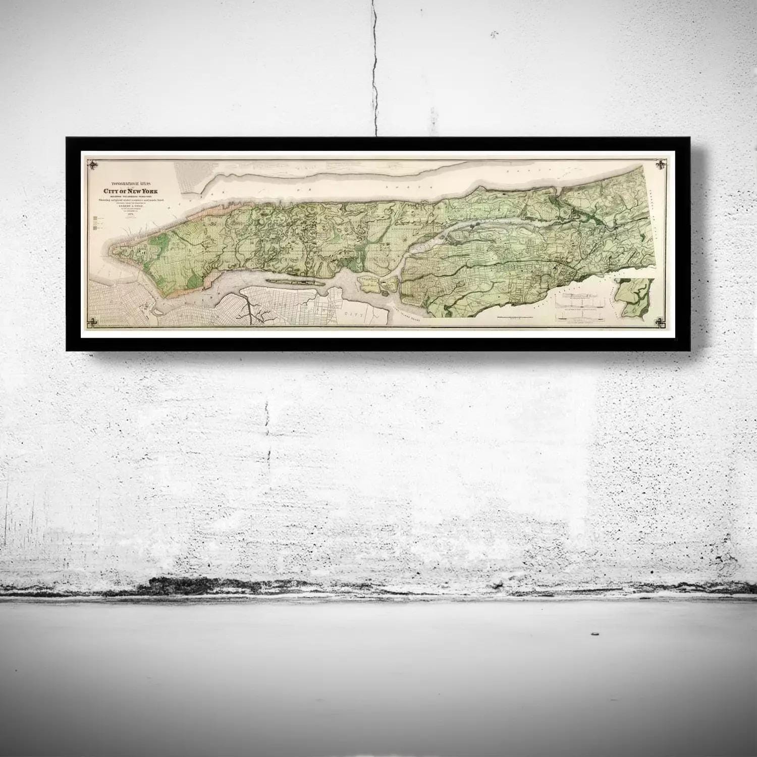 A framed map of New York City is hanging on a white wall.