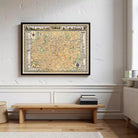 a framed map of Tehran hanging on a wall, with a wooden bench and some books placed in front of it.