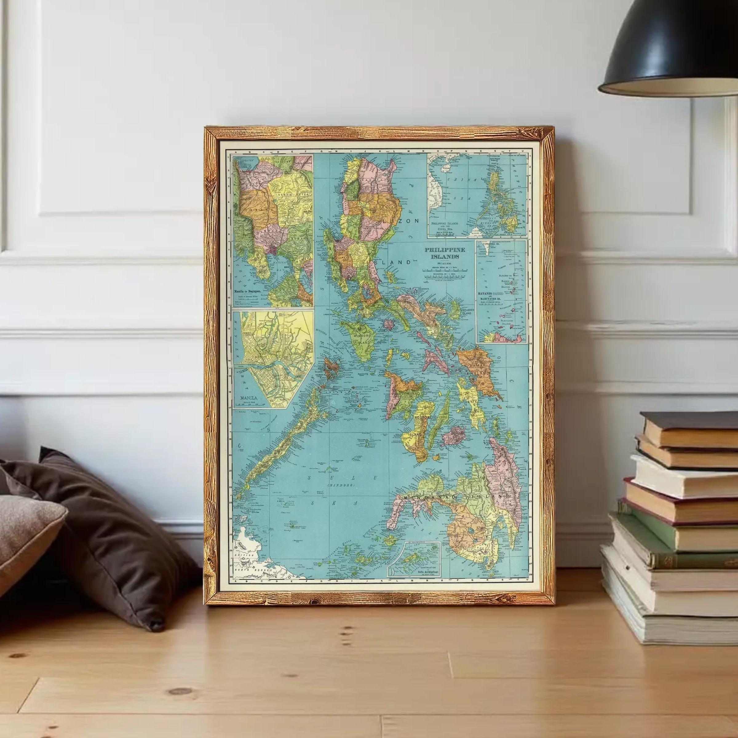 A framed vintage map of the Philippines is displayed on a wooden floor next to a stack of books.
