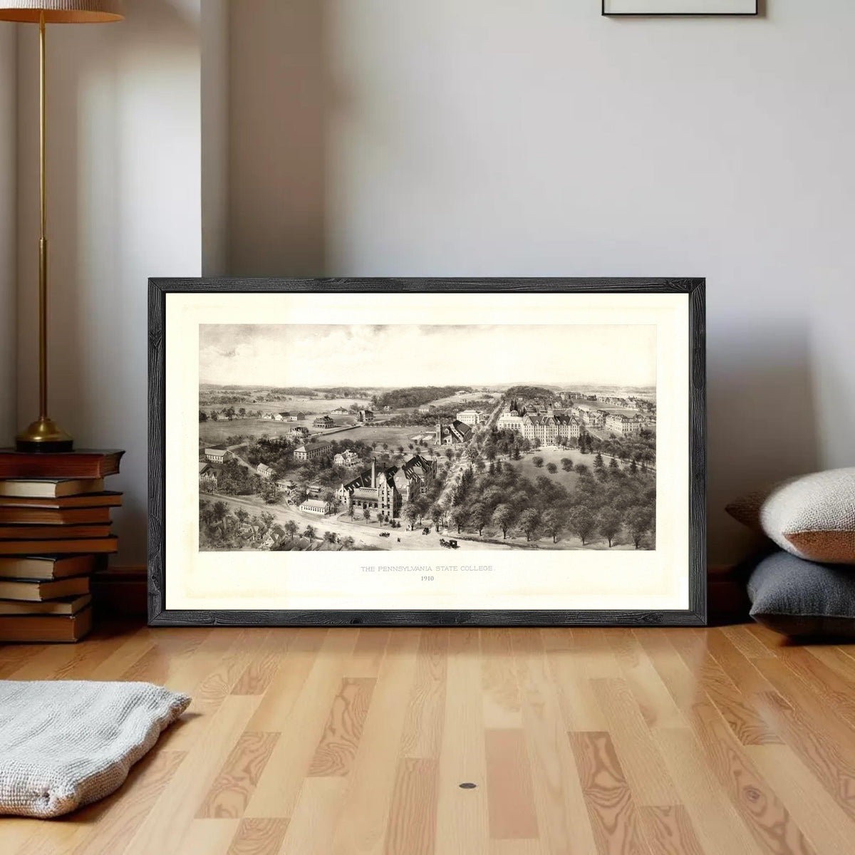 A framed black and white illustration of a landscape depicting a countryside scene with buildings and trees.