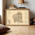 a framed map of Galicia, Spain, with a wooden frame and a lamp on a table in the background.