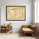 a large framed map of the Caribbean region hanging on a white wall in a room with a wooden side table and a brown sofa.