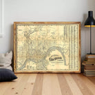 a large framed map of Cincinnati, Ohio, with a wooden frame and a black lamp on a wooden floor in the background.