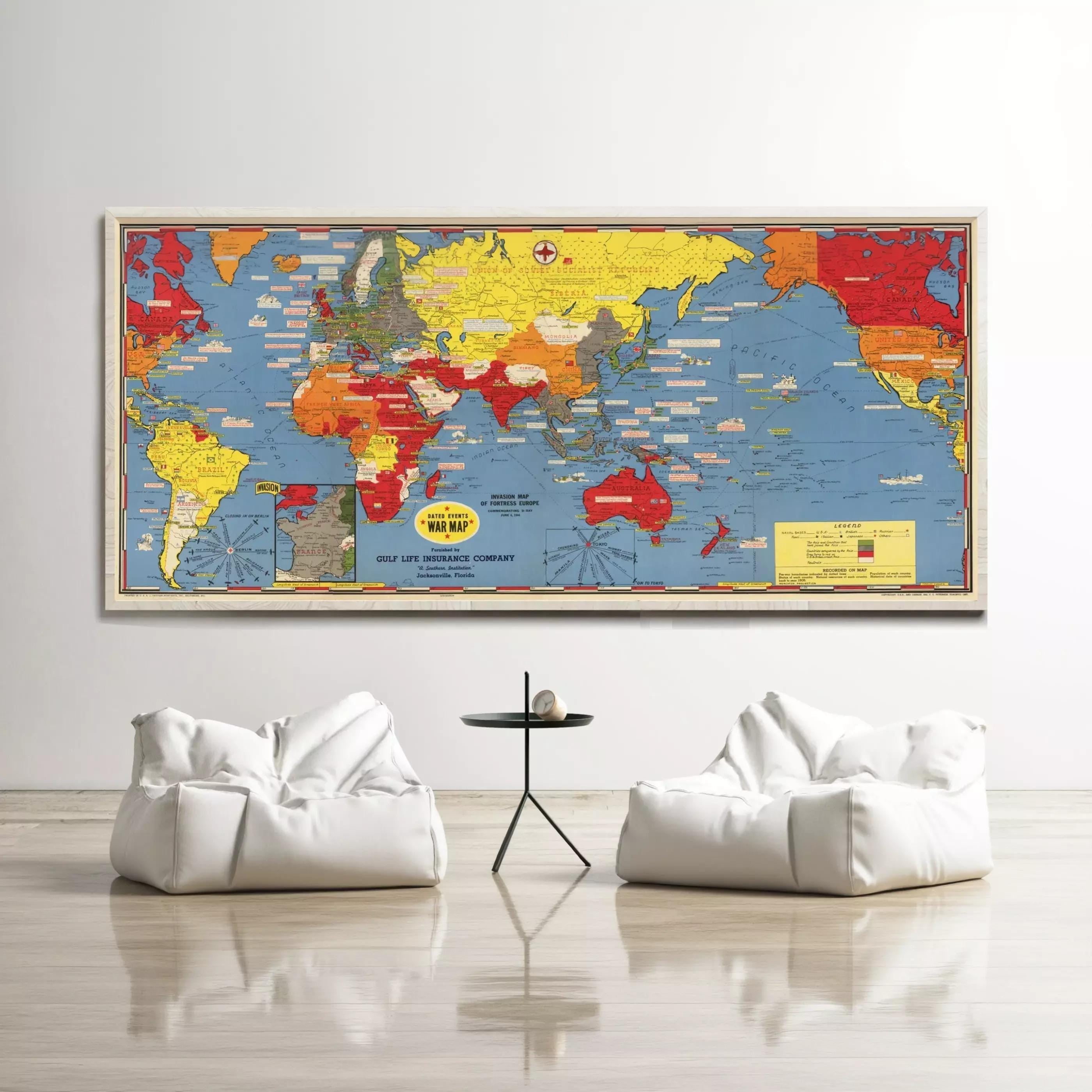 a large world map hanging on a wall, with a small table and two white bean bag chairs positioned in front of it.