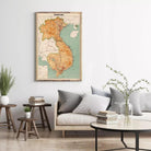 a living room with a large map of Vietnam hanging on the wall, a gray sofa with pillows, a wooden side table, and a round coffee table with a vase of flowers.