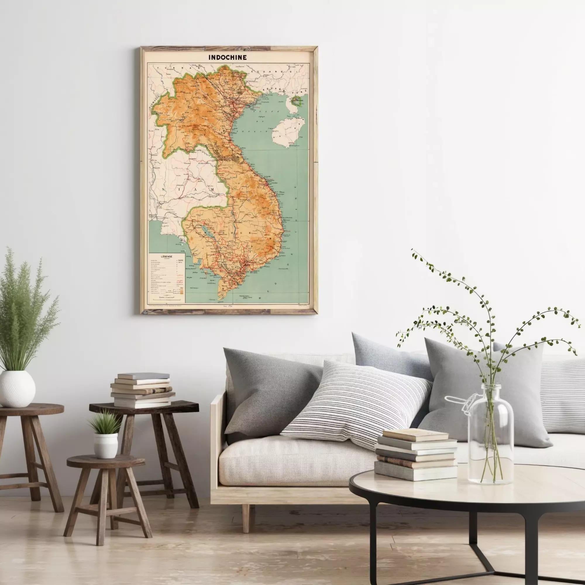 a living room with a large map of Vietnam hanging on the wall, a gray sofa with pillows, a wooden side table, and a round coffee table with a vase of flowers.