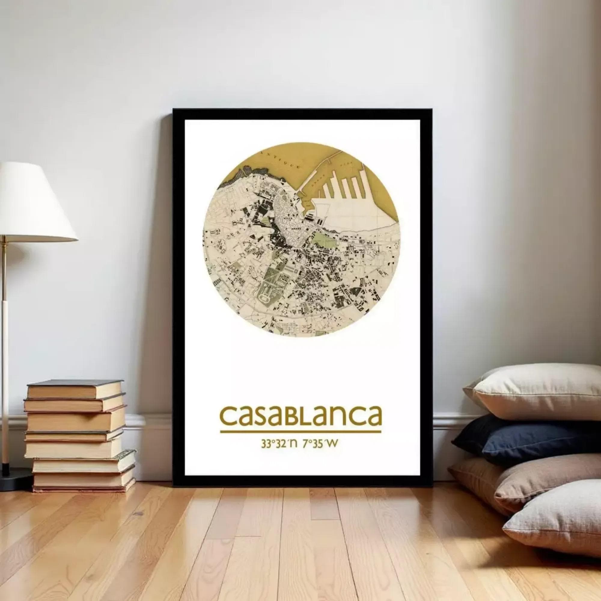 a framed poster of a map of Casablanca, with a stack of books and a lamp to the left of the frame.