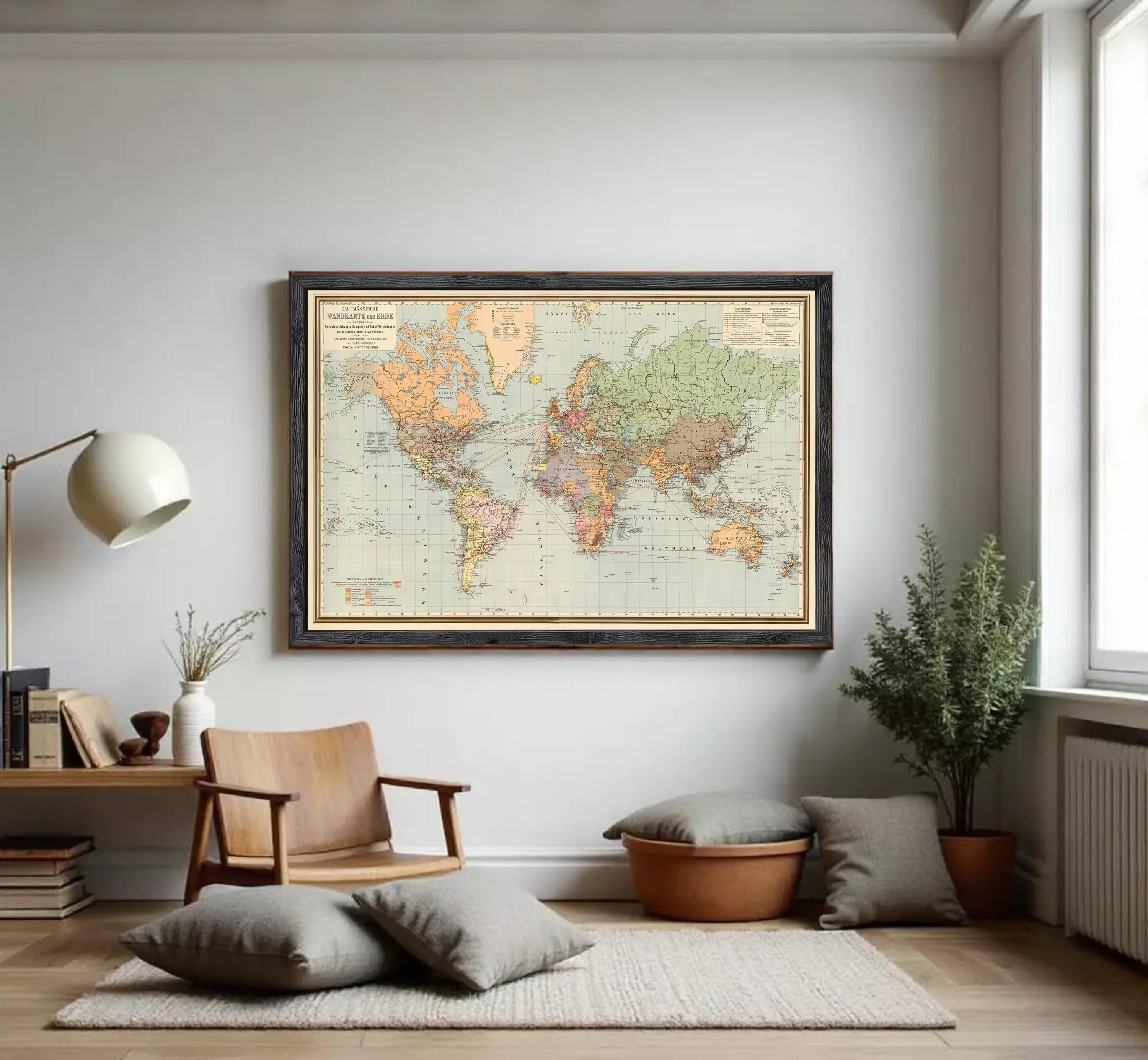 The image is a framed vintage world map with a black border and gold trim, displayed on a white wall.