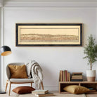 The image is a framed print of a historical map depicting a cityscape, with a white wall in the background.