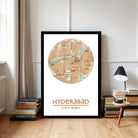 A framed map of Hyderabad, India, with a wooden floor and a stack of books in the background.