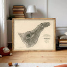 a framed map of the island of Sint Maarten, with a lamp and bookshelf in the background.